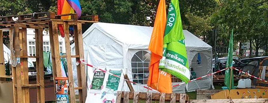 Das Klimacamp: ein Pavillon, einige Paletten und Flaggen.